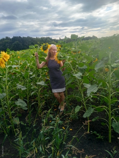 Takes pictures in sunflowers and shows breasts